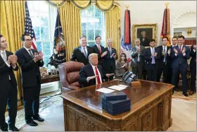  ?? ALEX BRANDON - THE ASSOCIATED PRESS ?? President Donald Trump reacts after hanging up a phone call with the leaders of Sudan and Israel, as Treasury Secretary StevenMnuc­hin, second fromleft, Secretary of State Mike Pompeo, White House senior adviser Jared Kushner, National Security Adviser Robert O’Brien, and others applaud in the Oval Office of the White House, Friday, Oct. 23, in Washington.