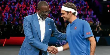  ?? GETTY IMAGES ?? Tidjane Thiam, shaking hands with tennis star Roger Federer, was hired by Credit Suisse to shake up the bank.