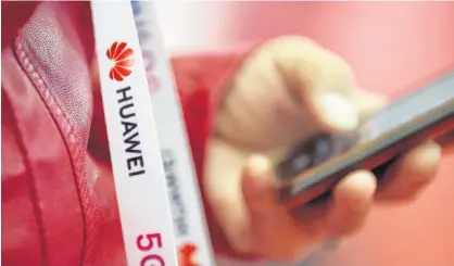  ?? JASON LEE/REUTERS ?? An attendee wears a badge strip with the logo of Huawei and a sign for 5G at the World 5G Exhibition in Beijing, China, last year.