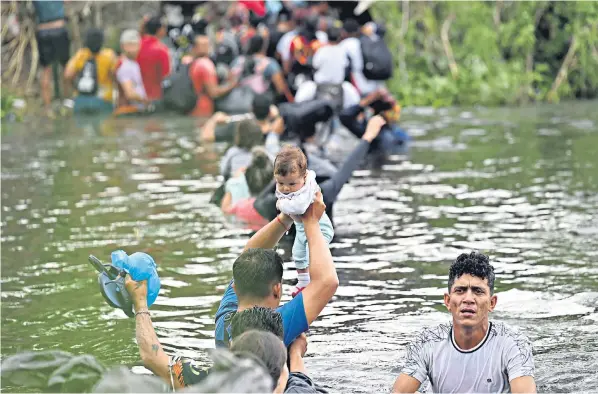  ?? ?? Migrants hold babies and belongings aloft as they cross the Rio Grande from Matamoros in Mexico to get to the United States