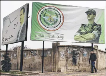  ?? HASSAN AMMAR / ASSOCIATED PRESS ?? ASyrian man walks by posters Monday of Syrian President Bashar Assad with Arabic that read “Homeland, honor, fidelity. Together we will build it,” in Aleppo, Syria. A Syrian war monitoring group says government forces have captured large parts of...