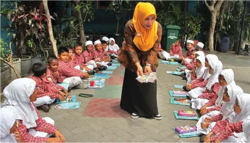  ?? HANUNG HAMBARA/JAWA POS ?? AYO AMBIL SATU: Nur Fitriyah menggunaka­n metode kekinian agar anak-anak semangat belajar. Sejauh ini siswanya enjoy dengan cara tersebut.