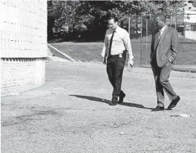  ?? KIM HAIRSTON/BALTIMORE SUN ?? Baltimore detectives Peter Johncox, left, and Kevin Brown investigat­e the scene at Mary E. Rodman Elementary School, where a 16-year-old was killed Tuesday.