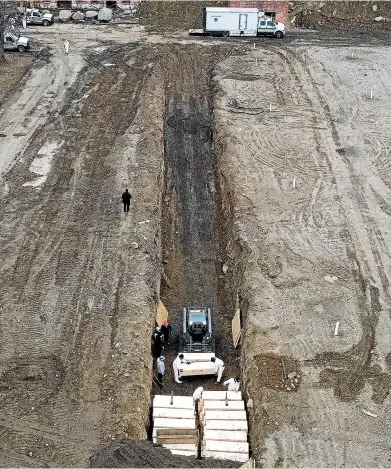  ?? AP ?? Workers wearing personal protective equipment bury bodies in a trench on Hart Island on Thursday in the Bronx borough of New York.