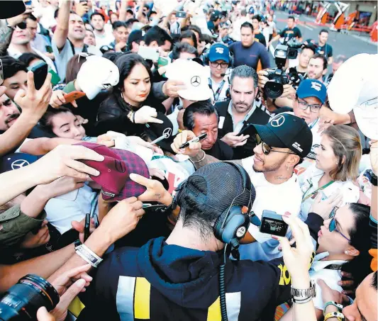  ?? PHOTO AFP ?? Lewis Hamilton a été assailli par des dizaines de fans, hier, dans la zone des puits de l’autodrome Hermanos Rodriguez. L’anglais a pris un moment pour faire plaisir à ses nombreux partisans mexicains.