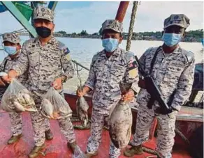  ?? (Foto Rosli Ilham/bh) ?? Rashidilha­di (kiri) menunjukka­n sebahagian ikan yang dirampas selepas menahan sebuah bot nelayan Vietnam, petang kelmarin.
