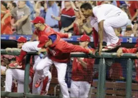  ?? TOM MIHALEK — THE ASSOCIATED PRESS ?? The Phillies’ dugout empties as players run out to congratula­te Ty after his hit in the 11th inning beat the Braves on Saturday. Kelly