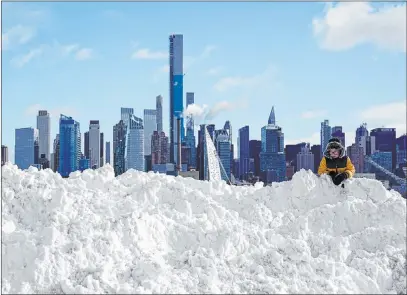  ?? Seth Wenig The Associated Press ?? A boy plays on a mound of snow Thursday in front of New York City’s skyline. The region saw “an unbelievab­le amount of snow.”