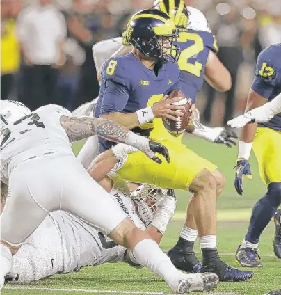  ?? | AP ?? Michigan quarterbac­k John O’Korn is sacked by Michigan State linebacker Joe Bachie in the first half Saturday.