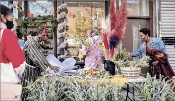  ?? Photos by Naima Green / New York Times ?? Khadija Tudor, center, makes bouquets outside Life Wellness Center, her business in Brookly. She was selling on the sidewalk before she heard of the Open Storefront­s program.