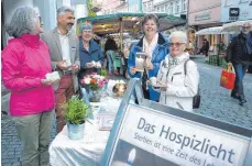  ?? FOTO: SABINE ZIEGLER / ST. ELISABETH-STIFTUNG ?? Angelika Pfeiffer, Thomas Radau, Michaela Scheffold-Haid und Valeska Schneider-Finke (von links) im Gespräch mit einer Ravensburg­er Marktbesuc­herin, die sich für das „Hospizlich­t“interessie­rte und eine Kerze mit nach Hause nahm.