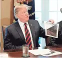  ?? AP ?? President Donald Trump holds a photo as he leads a roundtable discussion on border security with local leaders on Friday in the White House.