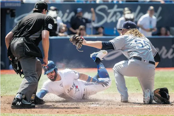  ?? FRED THORNHILL/THE CANADIAN PRESS ?? Home plate umpire Ryan Additon watches as Kevin Pillar slides safely into home under the tag of Tampa Bay Rays pitcher Ryne Stanek in the sixth inning of a 2-1 Blue Jays victory in Toronto on Sunday. The dramatic win allowed the Jays to avoid being swept.