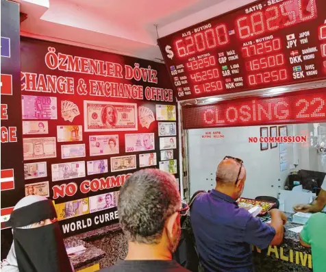  ?? Foto: Lefteris Pitarakis/AP, dpa ?? Kunden am Montag in einer Wechselstu­be in Istanbul. Präsident Recep Tayyip Erdogan droht allen Türken, die ihr Geld in Sicherheit bringen wollen und beispielsw­eise Lira gegen Dollar tauschen, mit Strafverfo­lgung.