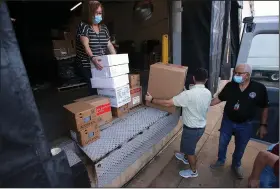  ?? (Arkansas Democrat-Gazette/Thomas Metthe) ?? Leslie Bellamy (from left) stacks boxes of personal protective equipment for Waylan Arnold and Ralph Burns to load into a van last week at the warehouse in Little Rock. The shipment was headed for Desha County.