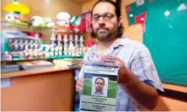  ??  ?? Gabriel Galvan, one of the founders of "La Ola Verde," or the Green Wave, poses with his accreditat­ion for the Confederat­ions Cup soccer game between Mexico and Russia, at his home in Mexico City. (AP)