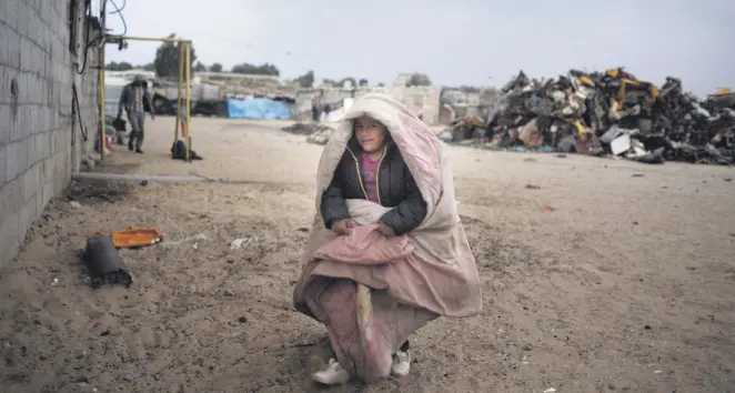  ??  ?? A Palestinia­n boy warms himself with a blanket, southern Gaza Strip, January 8, 2019.