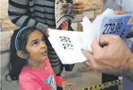  ??  ?? Nimisha Sandhu, 5, of Walnut Creek watches as store manager Charley Almassey hands out tickets for popular items at the Concord Toys R Us.