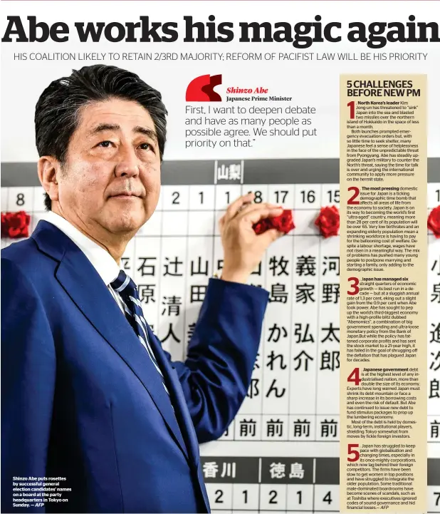  ?? AFP ?? Shinzo Abe puts rosettes by successful general election candidates’ names on a board at the party headquarte­rs in Tokyo on Sunday. —