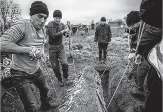  ?? Finbarr O’reilly/new York Times ?? Residents in Pravdyne, Ukraine, on Tuesday help police and war crimes investigat­ors exhume the body of a 15-year-old girl, who they said had been executed by Russian forces.