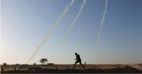  ??  ?? A PALESTINIA­N runs for cover from tear gas fired by Israeli troops during a protest at the Israel-Gaza border earlier this month.