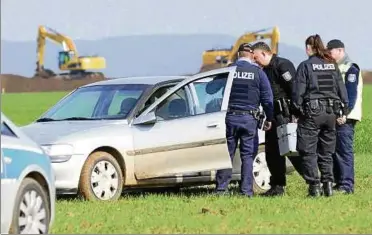  ??  ?? Polizeibea­mte aus Sömmerda sichern gestern am Morgen Spuren am verlassene­n Fluchtfahr­zeug, einem silbernen Opel, auf einem Feld in der Nähe des Windparkes Olberslebe­n. Fotos: Jens König ()