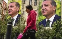  ?? EMRAH GUREL/ASSOCIATED PRESS ?? A pedestrian passes billboards of Turkish President Recep Tayyip Erdogan on Monday, a day after the presidenti­al election, in Istanbul, Turkey. Erdogan, who has ruled his country with a firm grip for 20 years, fell shy of the votes needed for an outright win.