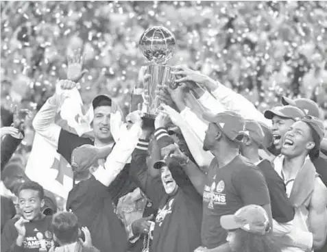  ?? ASSOCIATED PRESS ?? In this file photo, the Golden State players, coaches and owners hold up the Larry O’Brien Championsh­ip Trophy after Game 5 of the NBA Finals between the Warriors and the Cleveland Cavaliers in Oakland, California. The Warriors will begin their quest...