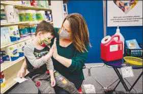  ?? NICOLE CRAINE / THE NEW YORK TIMES ?? Lauren Rymer encourages her son Jack, 6, with a high-five while getting his first dose of a COVID-19 vaccine Nov. 15 at a pharmacy in Lawrencevi­lle, Ga. Having children wait eight weeks or more between shots of a two-dose coronaviru­s vaccine may provide better, longer lasting immunity, but as omicron slams the U.S., waiting also comes with risks.