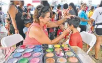  ??  ?? Dixie Blythe paints Marco Munoz’s face during the event.