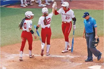  ?? AP PHOTO/NATE BILLINGS ?? Oklahoma’s Rylie Boone (0), Avery Hodge (82) and Tiare Jennings celebrate after Boone and Hodge scored against Stanford in the fifth inning of the Women’s College World Series opener for both teams Thursday in Oklahoma City. Top-seeded Oklahoma faces Tennessee on Saturday.