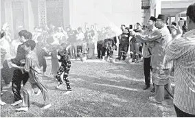  ??  ?? Awang Husaini (third from right) spraying 51 young boys with water before undergoing circumcisi­on at Al-Khautar Mosque yesterday.