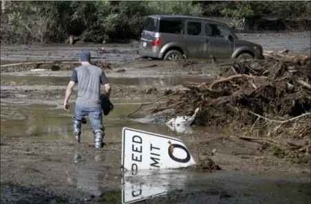  ?? MICHAEL OWEN BAKER — THE ASSOCIATED PRESS ?? Mitchell Barrett crosses mud from an overflown creek on Sheffield Drive in Montecito following the heavy rain, Tuesday. Barrett was going to check on his parents’ house in Montecito.