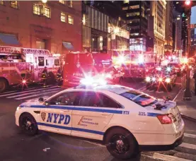  ?? EDUARDO MUNOZ ALVAREZ/GETTY IMAGES ?? New York police officers and first responders assess the scene of a fire at Trump Tower on April 7.