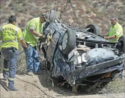  ?? Signal file photo ?? Tow truck operators work with a Toyota Corolla after it was lifted about 200 feet by a crane on to Lake Hughes Road north of Castaic on Sept. 30, 2011. David La Vau, the driver of the car, survived the crash. His daughter, Lisa, wrote a book on his ordeal.