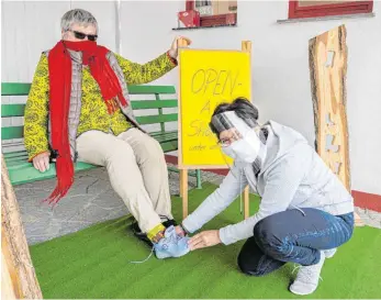  ?? FOTO: CLAUDIA BUCHMÜLLER ?? Versehen mit doppeltem Mundschutz, berät Silvia Kellinger die Kundin Lore Stützle beim „Open-Air-Shopping“im geschützte­n Carportber­eich.