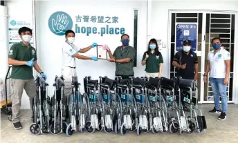  ?? — Photo courtesy of Hope Place ?? Hope Place founder Kelvin Wan (second left) presenting the new wheelchair­s to a social worker of the Sri Aman Hospital.