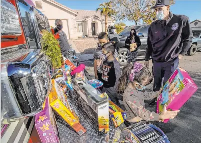  ?? L.E. Baskow Las Vegas Review-journal @Left_eye_images ?? From right: North Las Vegas Fire Department member Brandon Parry watches as Nolic, 5, and Auriel Alicea, 7, join brother Thomas Vasquez, 10, in checking out their new Christmas presents with mom Laura Alicea looking on Wednesday.