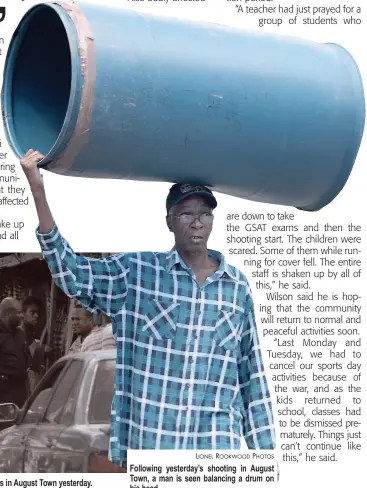  ?? LIONEL ROOKWOOD PHOTOS ?? A cop holds on tightly to a suspect in the shooting of five persons in August Town yesterday. Following yesterday’s shooting in August Town, a man is seen balancing a drum on his head.