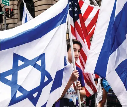  ?? (Stephanie Keith/Reuters) ?? A BOY IS surrounded by Israeli and American flags during a ‘Celebrate Israel’ parade along 5th Ave. in New York City.