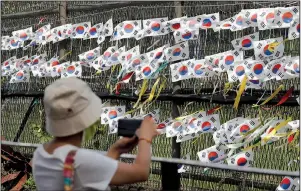  ?? AP/LEE JIN-MAN ?? A visitor in Paju, South Korea, takes photos Sunday near a fence decorated with South Korean flags and ribbons with messages calling for the reunificat­ion of the two Koreas. The North Koreans have conducted five weapons tests since July 25, according to South Korea.