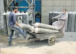  ?? AP ?? Workers load oxygen cylinders onto a hand cart to be carried inside the Covid-19 wards at a government-run hospital in Jammu on Friday.