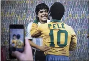  ?? PHOTO BY JUAN MABROMATA — AFP VIA GETTY IMAGES ?? A man takes a picture of a wall depicting images of late soccer stars Diego Maradona of Argentina and Pelé of Brazil.