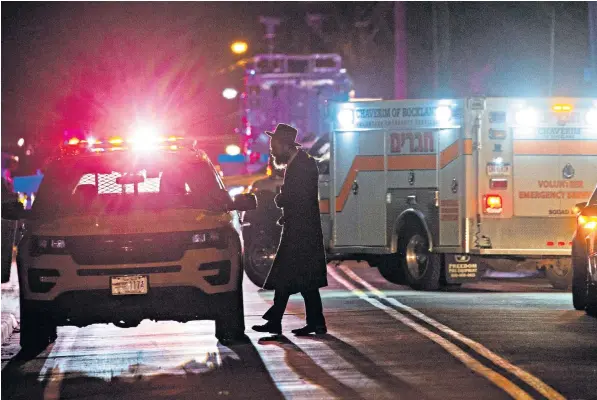  ??  ?? A Jewish man walks near the area where five people were injured at a Hasidic rabbi’s home on Saturday night in Monsey, about 35 miles north of the city of New York