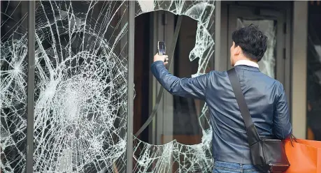  ??  ?? Vetri rottiUn passante scatta una foto a una delle tante vetrine rotte dopo gli scontri di sabato a Parigi tra giletjaune­s e polizia