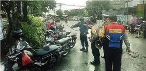  ?? FAJAR TUMANGGOR/JAWA POS ?? KAWASAN RENTAN: Anggota Polsek Mulyorejo menyemprot kendaraan yang parkir di Pasar Yamuri, Kalisari, kemarin pagi.