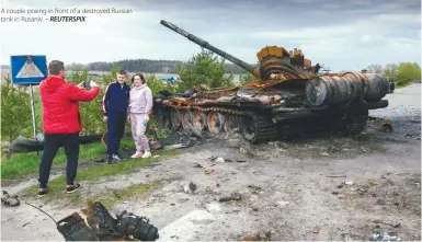  ?? REUTERSPIX ?? A couple posing in front of a destroyed Russian tank in Rusaniv. –