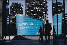  ?? LUCA BRUNO — THE ASSOCIATED PRESS FILE ?? A man and a girl on a scooter are backdroppe­d by a Lombardy region campaign advertisin­g reading in Italian “Coronaviru­s let’s stop it together” at the Porta Nuova business district in Milan.