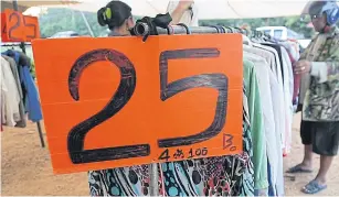  ??  ?? Second-hand clothes sell for as low as 25 baht apiece at a flea market in Chainat province.