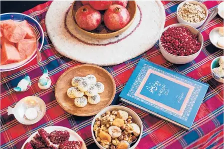  ?? MAX WHITTAKER/THE NEW YORK TIMES ?? Foods for Shab-e Yalda include, clockwise from top: pomegranat­es; hogweed to sprinkle on pomegranat­e seeds; baslogh (soft and chewy rosewater-infused walnut sweets); ajeel (mixed nuts, seeds and dried fruit); rice cookies and watermelon.